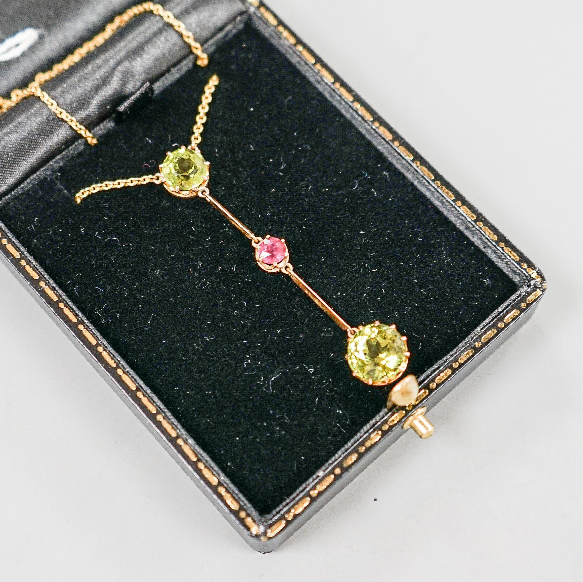 A 20th century yellow metal, two stone peridot and single stone pink tourmaline? set drop line pendant necklace, 51cm, gross 5.5 grams.
